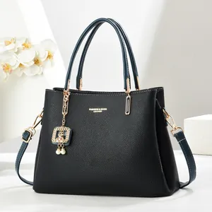 Détail du sac à main en cuir noir grainé avec ferrures dorées et breloque perle
