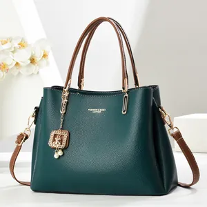 Sac à main vert en cuir grainé avec bandoulières brunes et pendentif d'ours