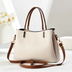 Détail du sac à main en cuir crème avec poignées marron et finitions dorées