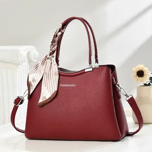Detail of wine red crossbody bag featuring lychee grain texture and decorative scarf handle