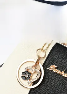 Gros plan sur le pendentif cœur doré et la texture du cuir grainé du sac à main