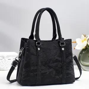 Large black pleated leather handbag with top handles and adjustable shoulder strap