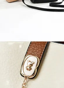 Detail of a golden bear ornament on a beige pebbled leather bucket bag with brown strap