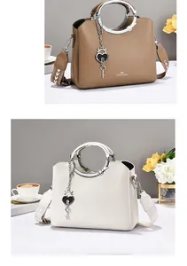Detail of leather tote with metal ring handle, woven strap and luxury heart pendant