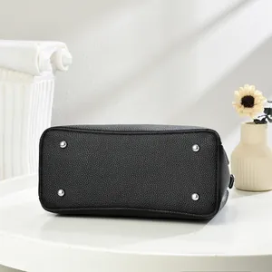Detail of black pebbled leather handbag base with silver metal protective feet