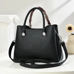 Close-up of black lychee texture handbag with checkered silk scarf on the handle