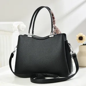 Detail of black litchi grain handbag featuring silk scarf wrap and silver hardware