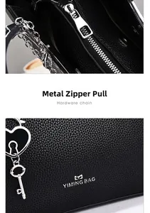 Detail of black lychee grain leather handbag with silver hardware and heart keychain