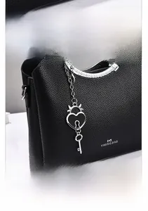 Detail of black lychee grain leather handbag with silver heart-shaped lock pendant