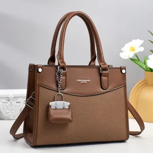 Elegant brown leather and woven tote bag with a mini charm and crossbody strap