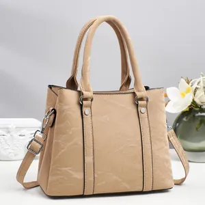 Detail view of khaki faux leather handbag with silver metal hardware and adjustable strap