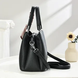 Detail of black pebbled leather handbag with silk scarf and silver hardware accents