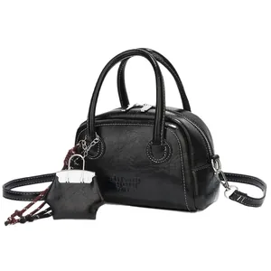 Chic black glossy square handbag with white contrast stitching and a star charm