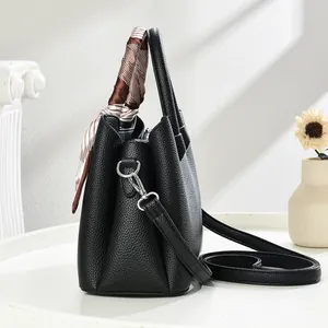 Detail of black pebbled leather tote bag with silk scarf on handle and silver hardware
