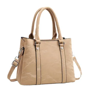 Chic beige textured faux leather handbag with top handles and a long shoulder strap
