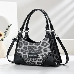 Fashionable leopard print handbag with black trim, metal rivets and adjustable shoulder strap