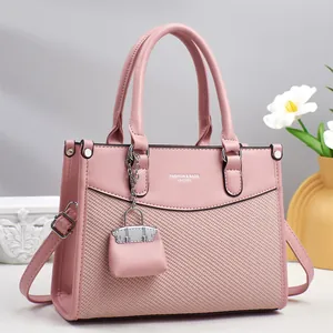 Detail of soft pink tote bag featuring woven leather texture and silver metal hardware