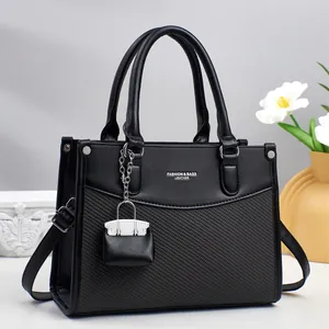 Close-up of black tote bag featuring woven texture and a mini bag decorative charm