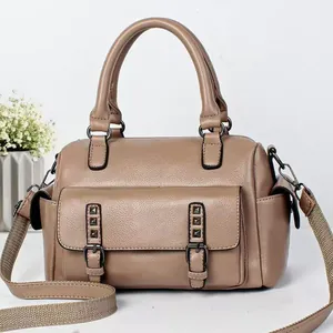 Detailed view of khaki pebbled leather handbag with woven strap and metal rivets