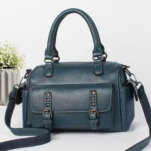 Detail of teal pebble leather handbag featuring vintage rivets and canvas shoulder strap