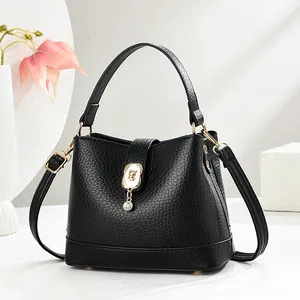 Sac seau noir minimaliste en cuir grainé avec pendentif ours doré et bandoulière