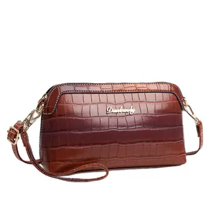 Fashionable dark brown crocodile pattern crossbody bag with golden hardware and brand logo