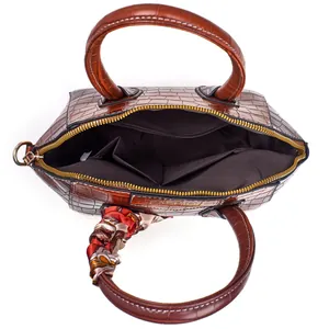 Draufsicht der braunen Krokodil-Handtasche mit Seidenschal und goldener Plakette innen
