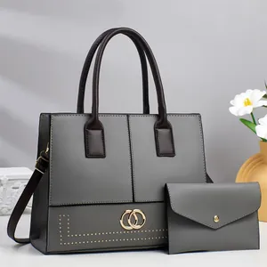 Detail view of grey leather tote with gold studs and matching envelope bag set