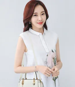 Detalle de bolso crema texturizado con herrajes dorados y blusa blanca de flores