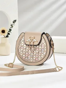 Sac bandoulière beige évidé avec fermoir cygne et pompon perlé sur fond minimaliste