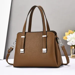 Détail du sac à main en cuir marron foncé avec motif litchi et boucles en métal argenté