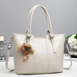 Detail of cream white bucket bag with pebble texture and cute plush charm accessory