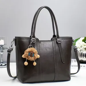 Detail of dark brown leather bucket bag with plush charm and adjustable shoulder strap