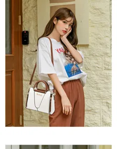 Detailed close-up of a white and brown contrast tote bag featuring gold hardware accents