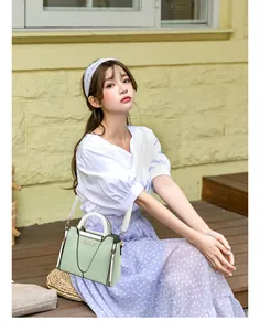 Detail of mint green and white Danbaoly handbag with gold logo and smooth PU leather finish