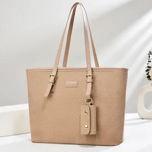 Close-up of beige woven tote bag with refined gold buckles and matching small pouch