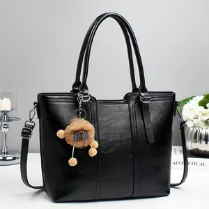 Elegant black leather bucket bag with vertical stitching and a cute monster charm accessory