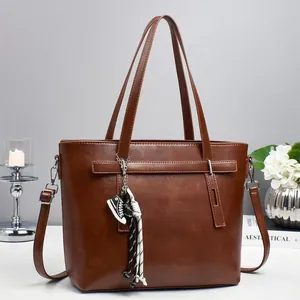 Brown faux leather tote bag with shoulder strap, decorative charms and a top handle