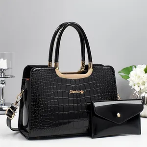 Détail d'un sac à main noir gaufré crocodile et d'un portefeuille assorti avec dorures