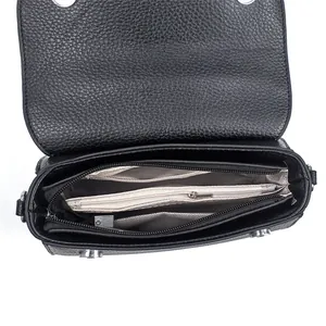 Détail du sac bandoulière en cuir grainé noir montrant les deux compartiments zippés internes