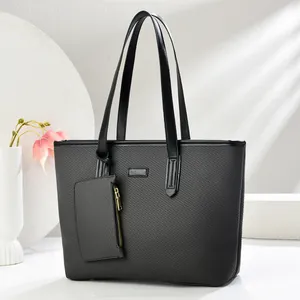Minimalist black woven tote bag with dual leather handles and a mini detachable pouch