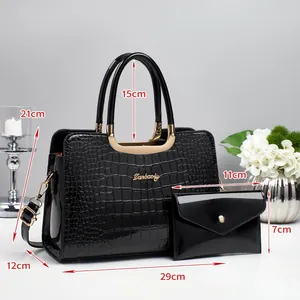 Vue détaillée du sac à main noir brillant à motif crocodile avec dimensions et logo