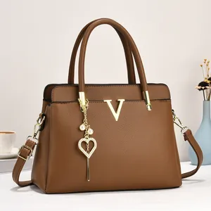 Détail du sac cabas caramel grainé avec logo V doré et breloque cœur en perle