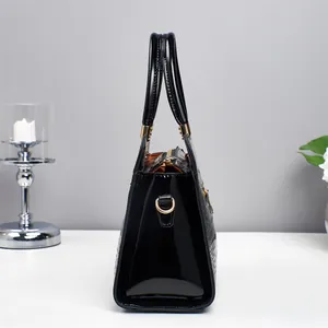 Détail de sac à main noir en similicuir avec texture crocodile et ferrures dorées