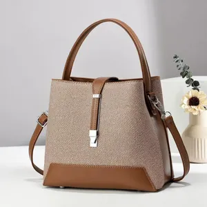 Elegant beige canvas and brown leather bucket bag with silver buckle and top handle