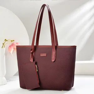 Detail of burgundy tote bag with woven texture, fashion label and gold hardware