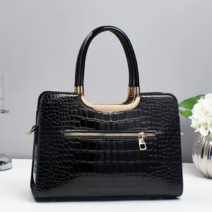 Détail du sac à main noir à motif crocodile avec des finitions métalliques dorées