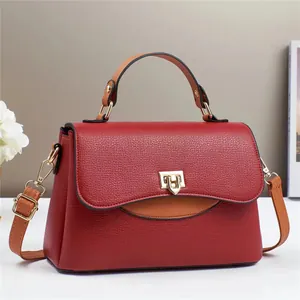 Détail du sac en cuir bicolore rouge et marron avec fermoir doré et poignée ronde