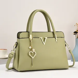 Détail du sac à main vert olive en cuir grainé avec logo V doré et pendentif cœur en perle