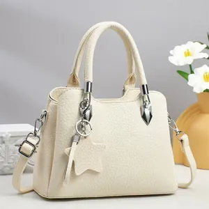 Minimalist beige pebble leather tote bag with star charm on white marble base